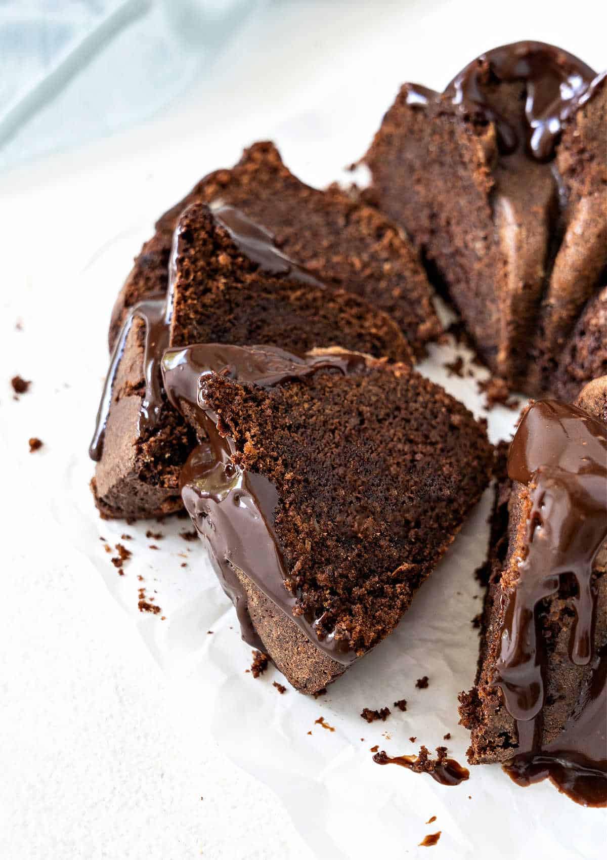 Sliced glazed chocolate whisky (bourbon) bundt cake on a white surface.