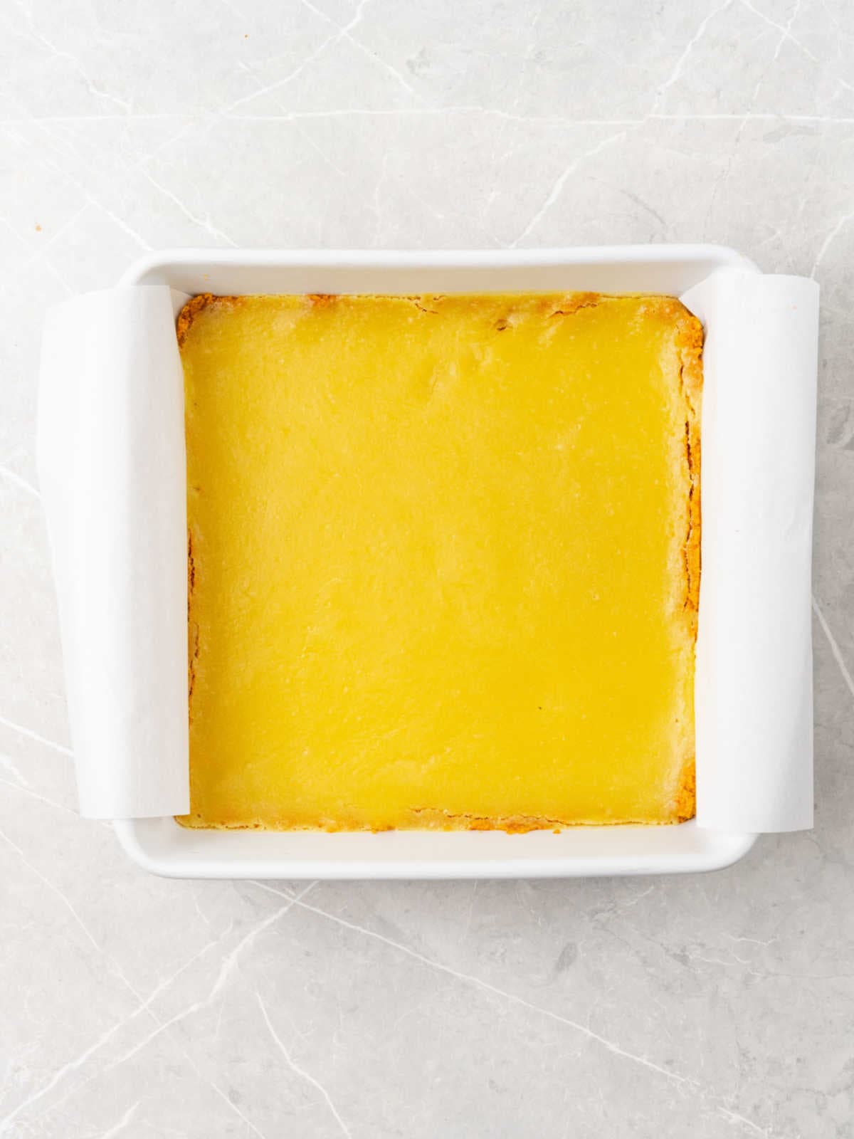 Baked white pan with lemon bars on a light gray surface.