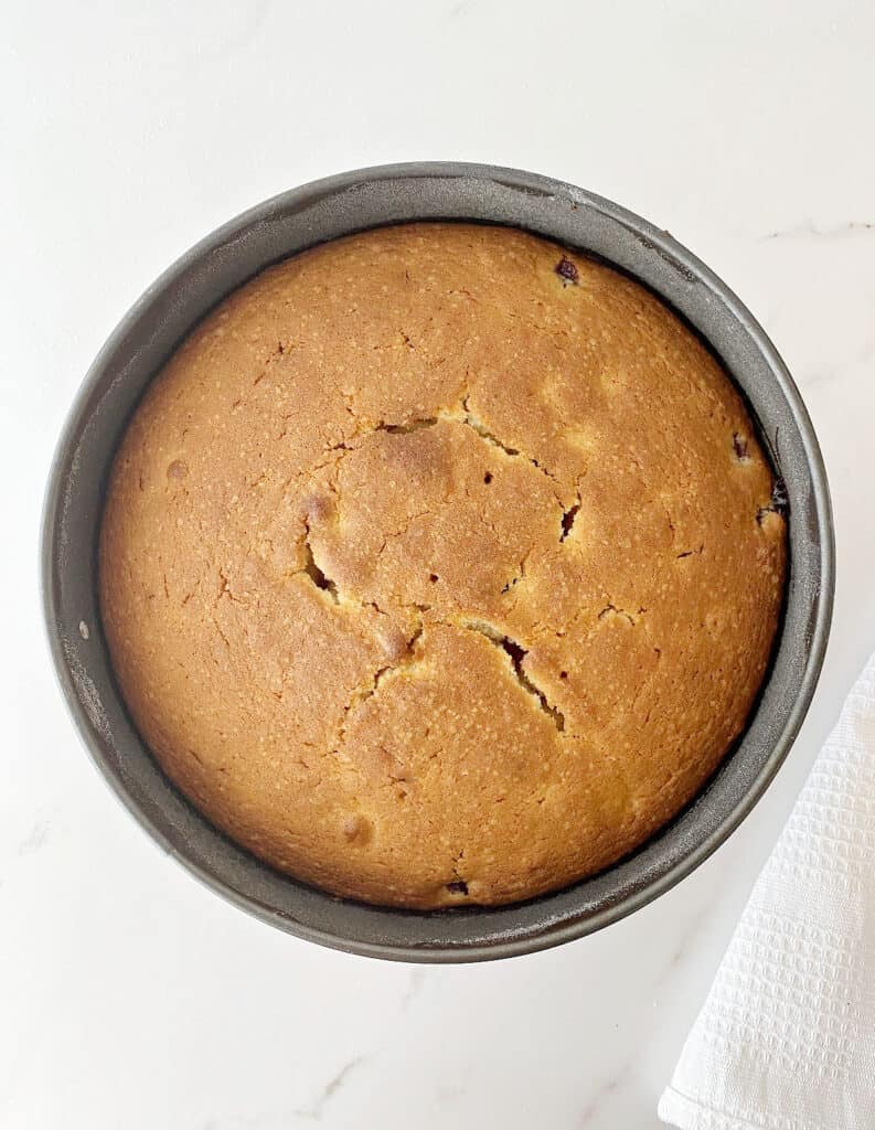 White marbled surface with round metal pan with baked cake. Top view.