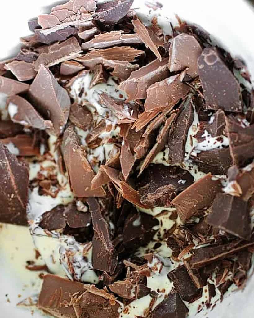 Close up of milk and dark chocolate pieces in a white bowl.