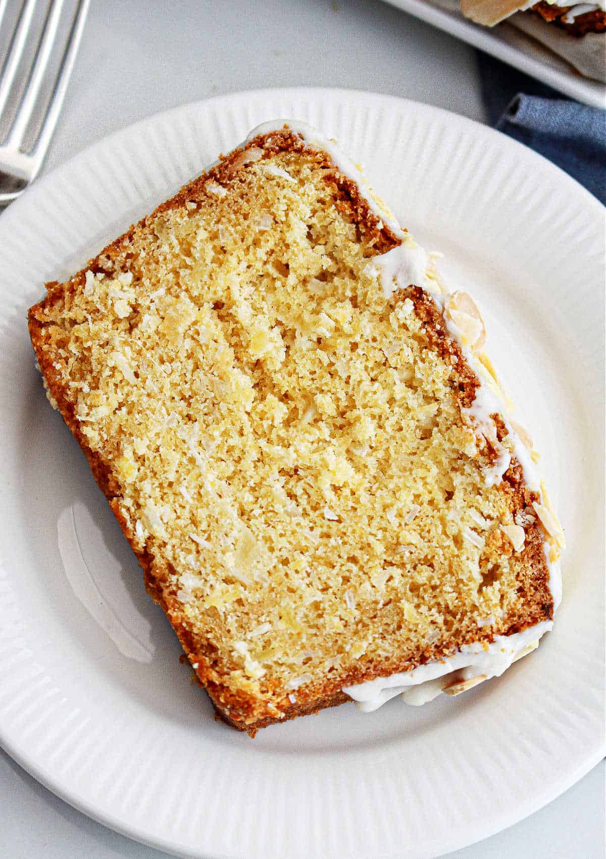 Single slice of coconut pineapple bread with glaze on a white plate.