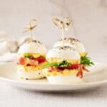 Three BLT deviled egg sandwiches on a white plate. Whitish grey surface and background.