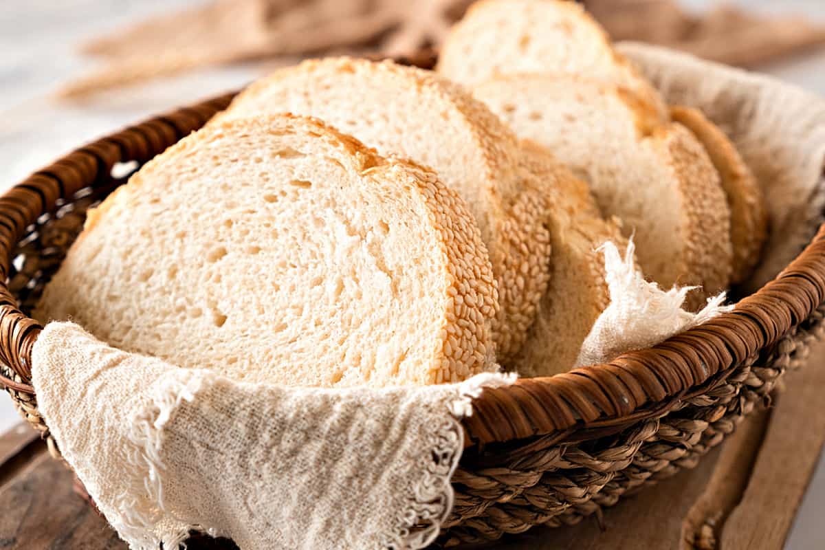 Dark basket with semolina bread slices on a beige towel.