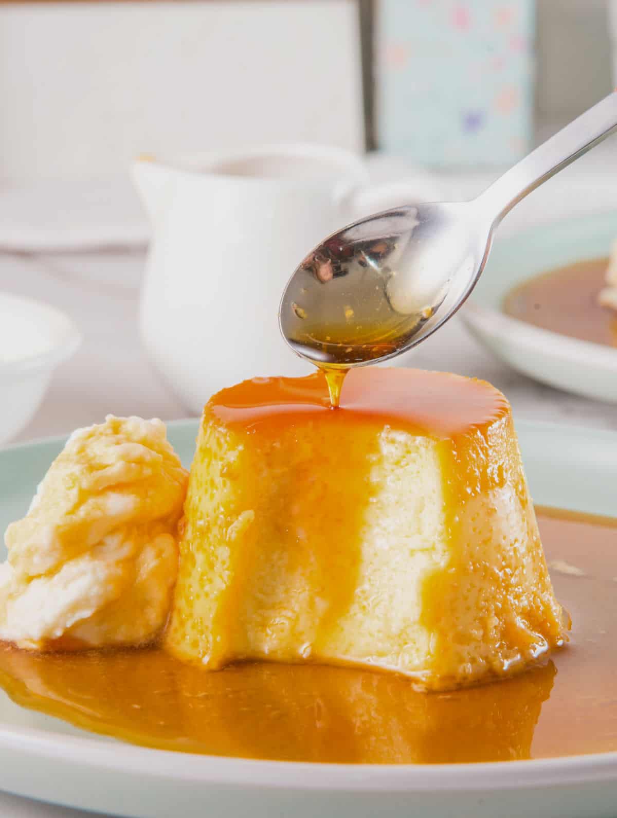 Half eaten flan serving with caramel and cream on a plate.