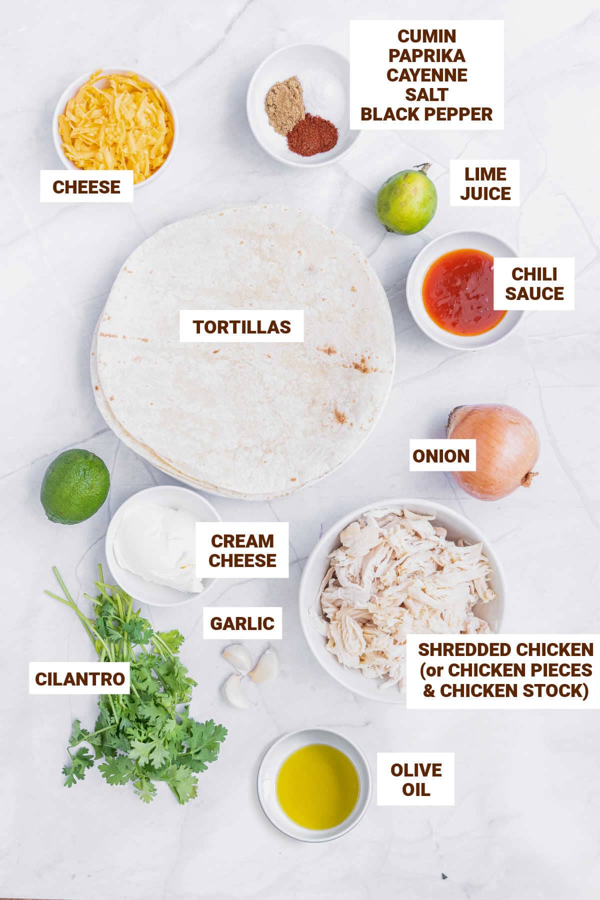 Ingredients for spiced chicken taquitos in bowls on a white surface.