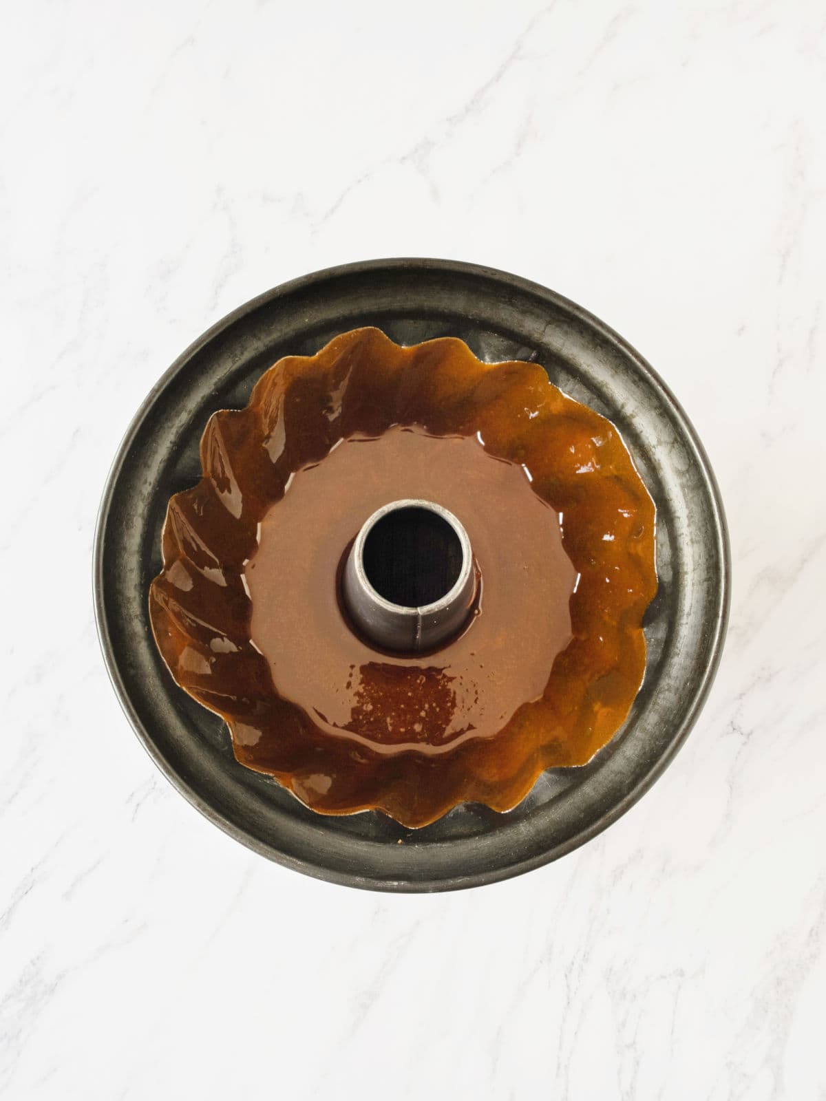 Caramelized dark bundt pan on white marble. 