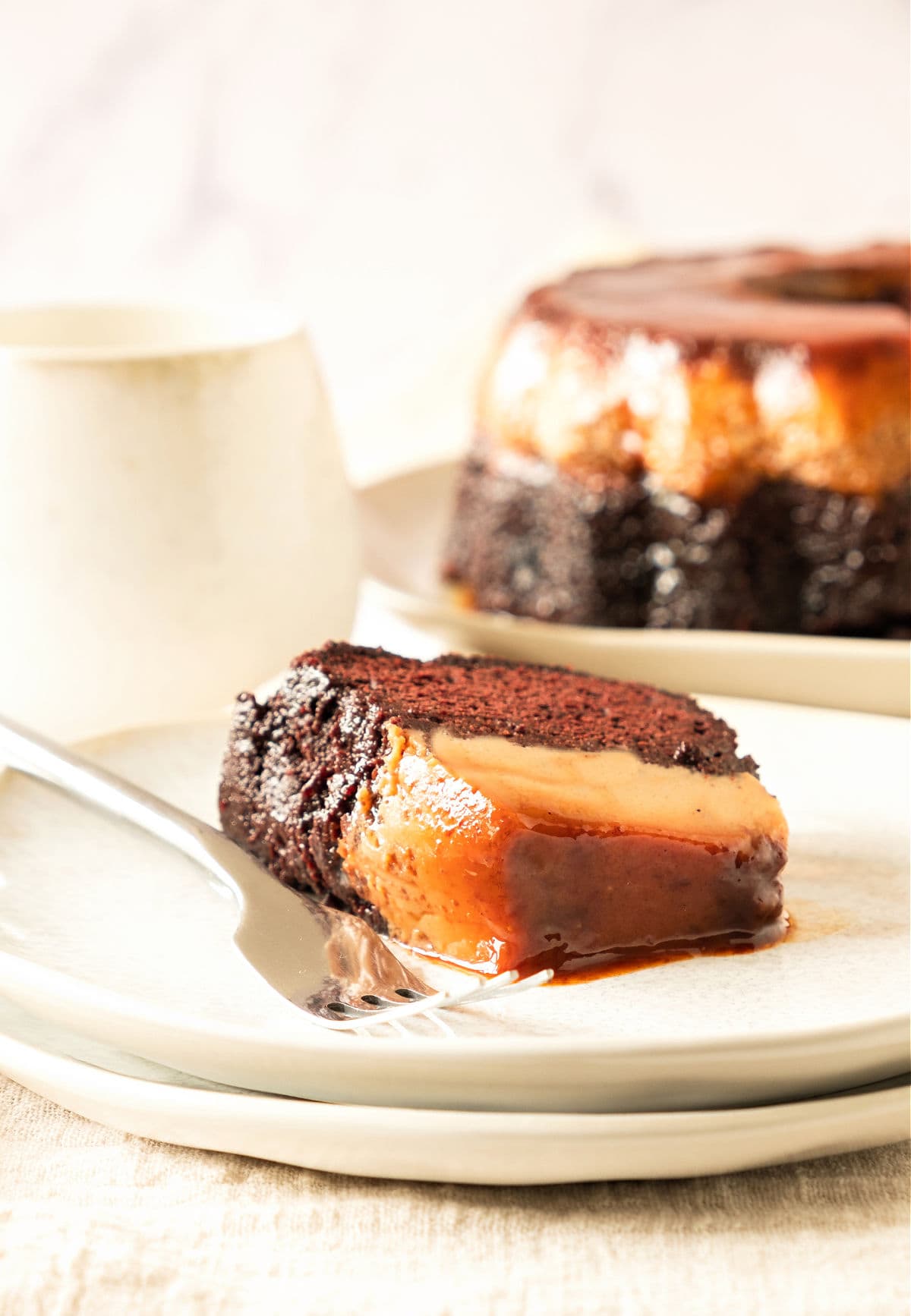 White background and plates with chocoflan slice and whole cake. 