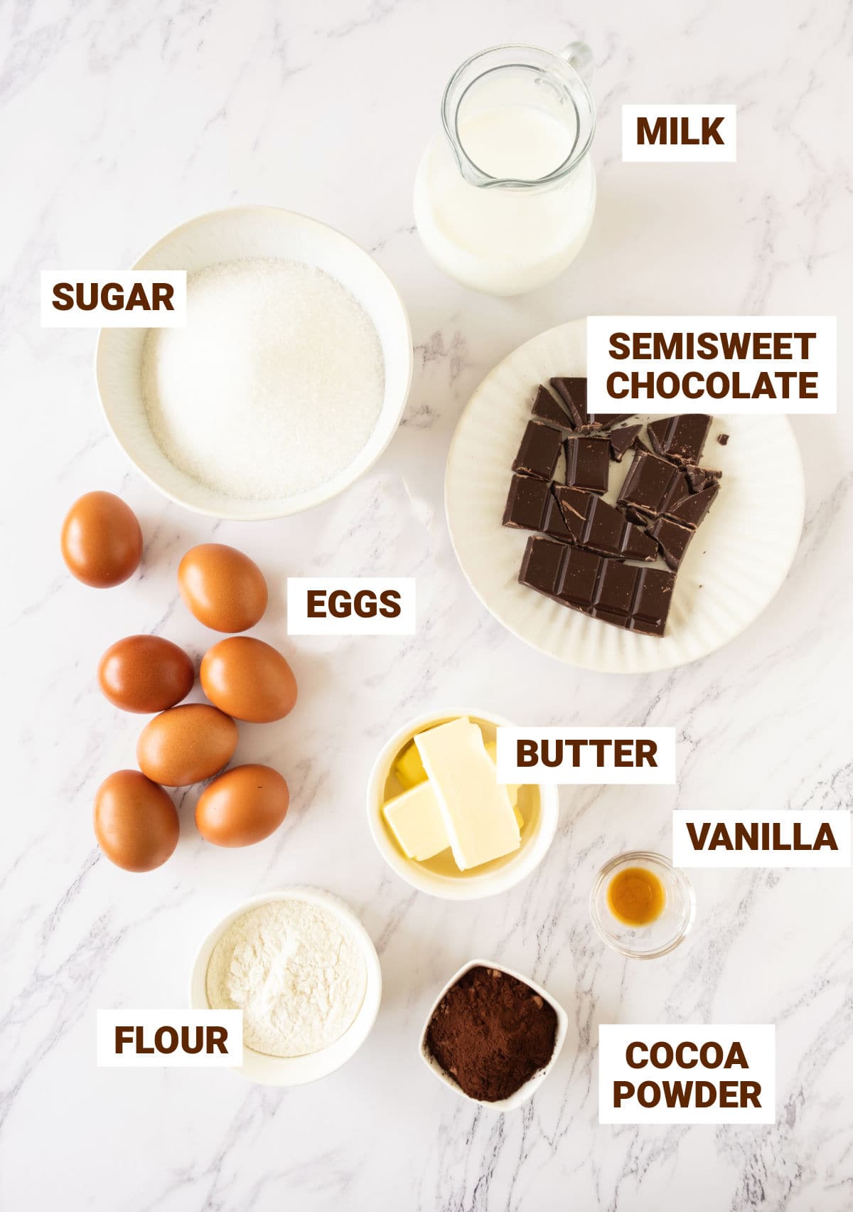 Ingredients for chocoflan in bowls on a white marbled surface.