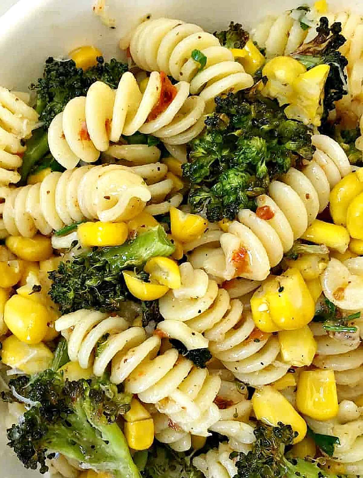 Very close up of fusilli pasta with corn, broccoli and harissa paste. 