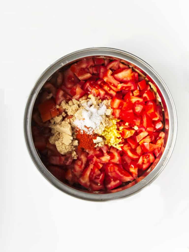 Ingredients for homemade ketchup in a metal saucepan. White surface. 