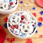 White bowl with homemade patriotic muddy buddies. Wooden surface, colored jelly stars around.