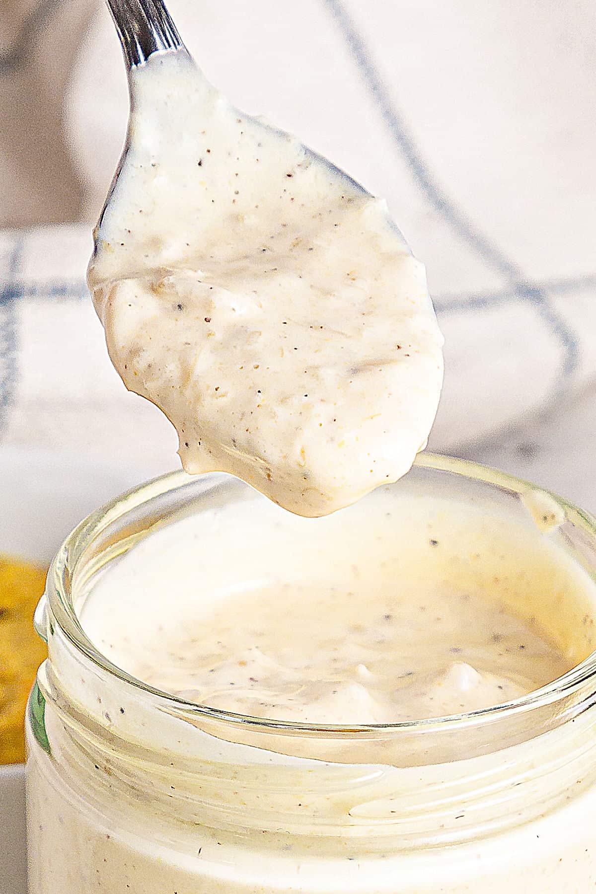 Aioli in a jar being spooned. White background. 