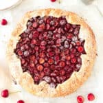 Whole baked cherry galette on a white surface.