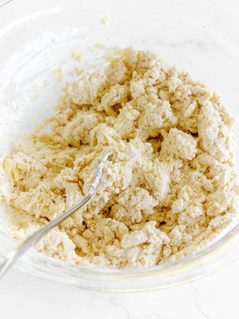 Silver fork in a glass bowl with shaggy scone dough.