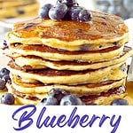 White, blue and red text overlay on two images of stack and bite of blueberry pancakes.