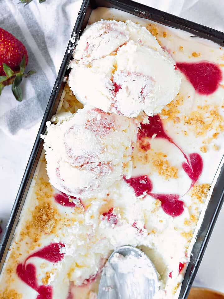 Strawberry ice cream in the metal loaf pan, some scoops. Fresh strawberries.