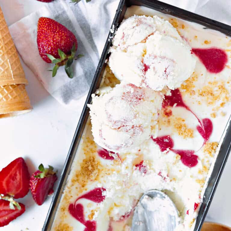 Strawberry ice cream in the metal loaf pan, some scoops. Fresh strawberries.