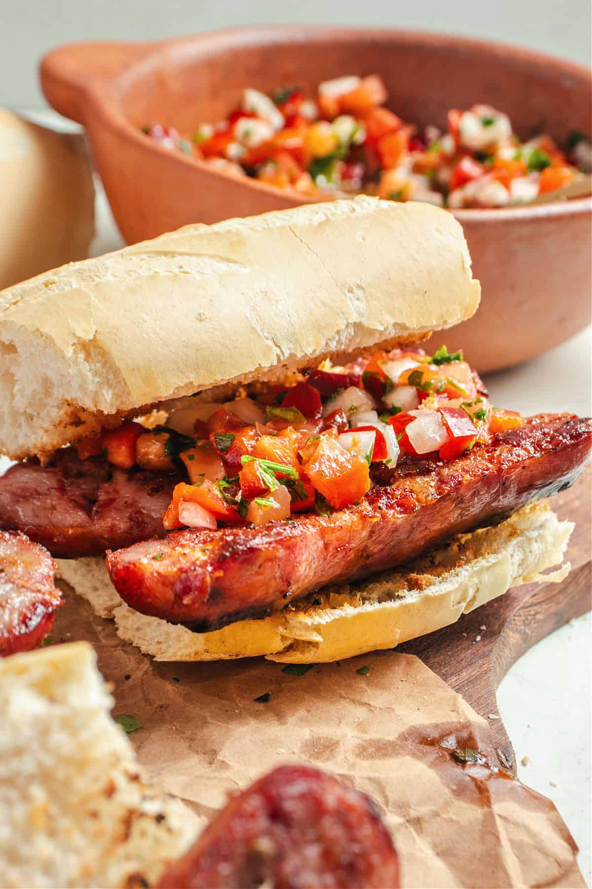 Chorizo chimichurri sandwich with salsa. White bread, wooden board, bowl with salsa.