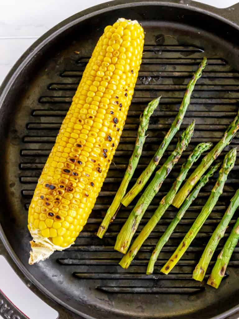 Grilled corn and asparagus spears on a cast-iron ridged skillet.