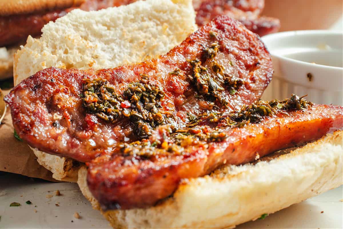 Chimichurri-topped chorizo open sandwich in crusty French bread.