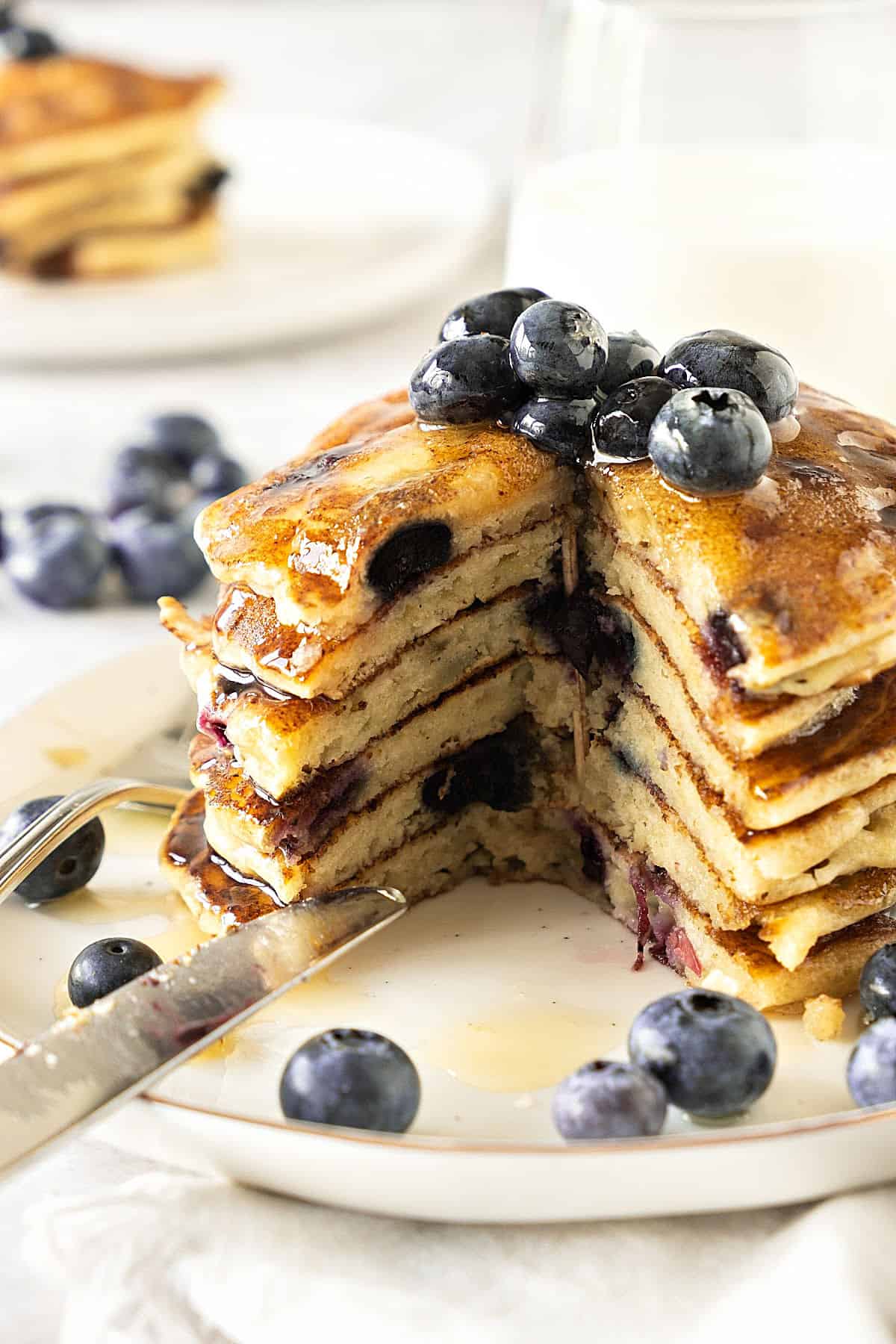 Cut blueberry pancakes in a stack on a white plate. White background.