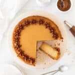 Close up top view of pink plate with dulce de leche cheesecake. Cut slice. White background.