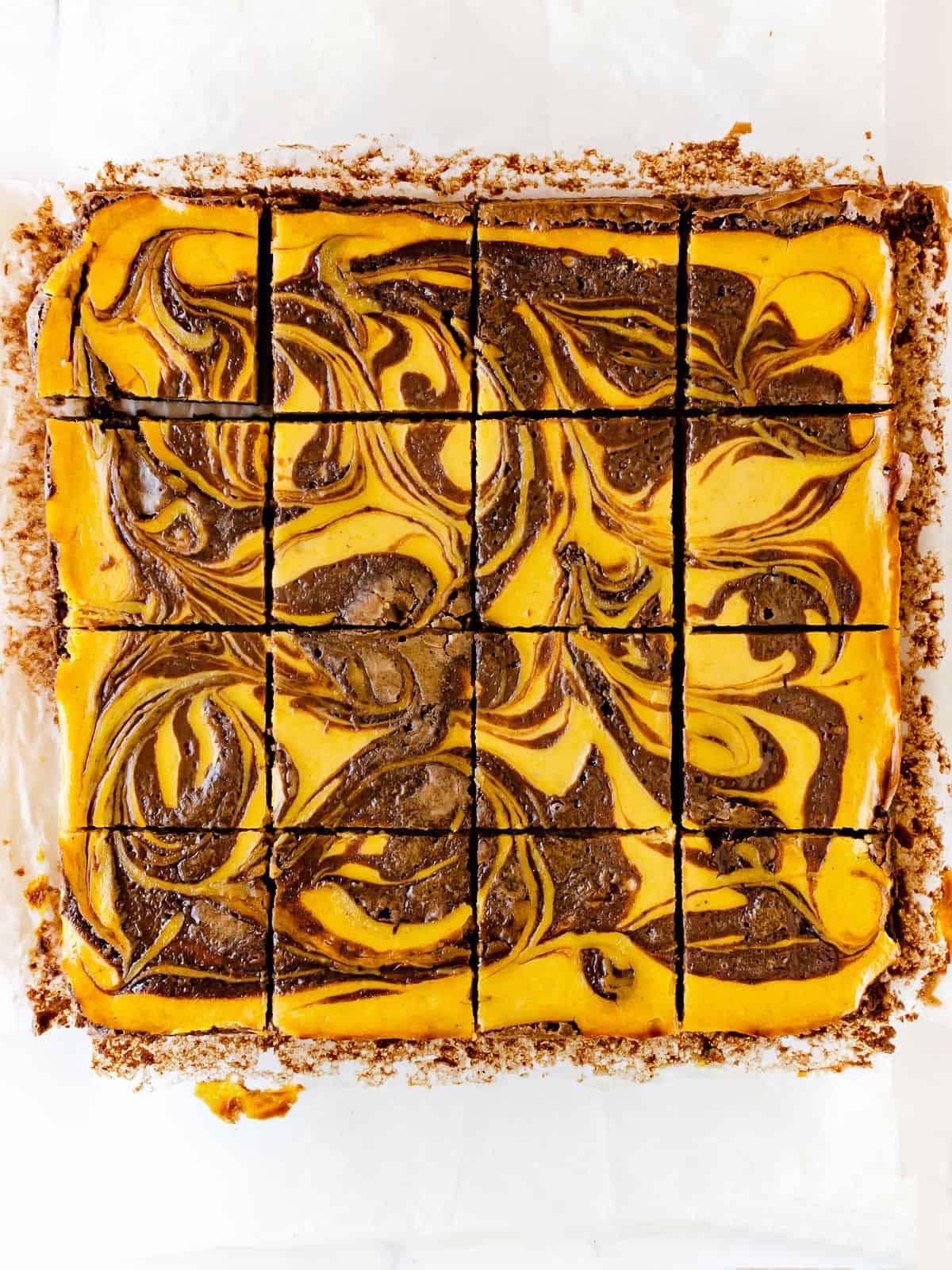 Baked square of cut pumpkin brownies on white paper. Top view.