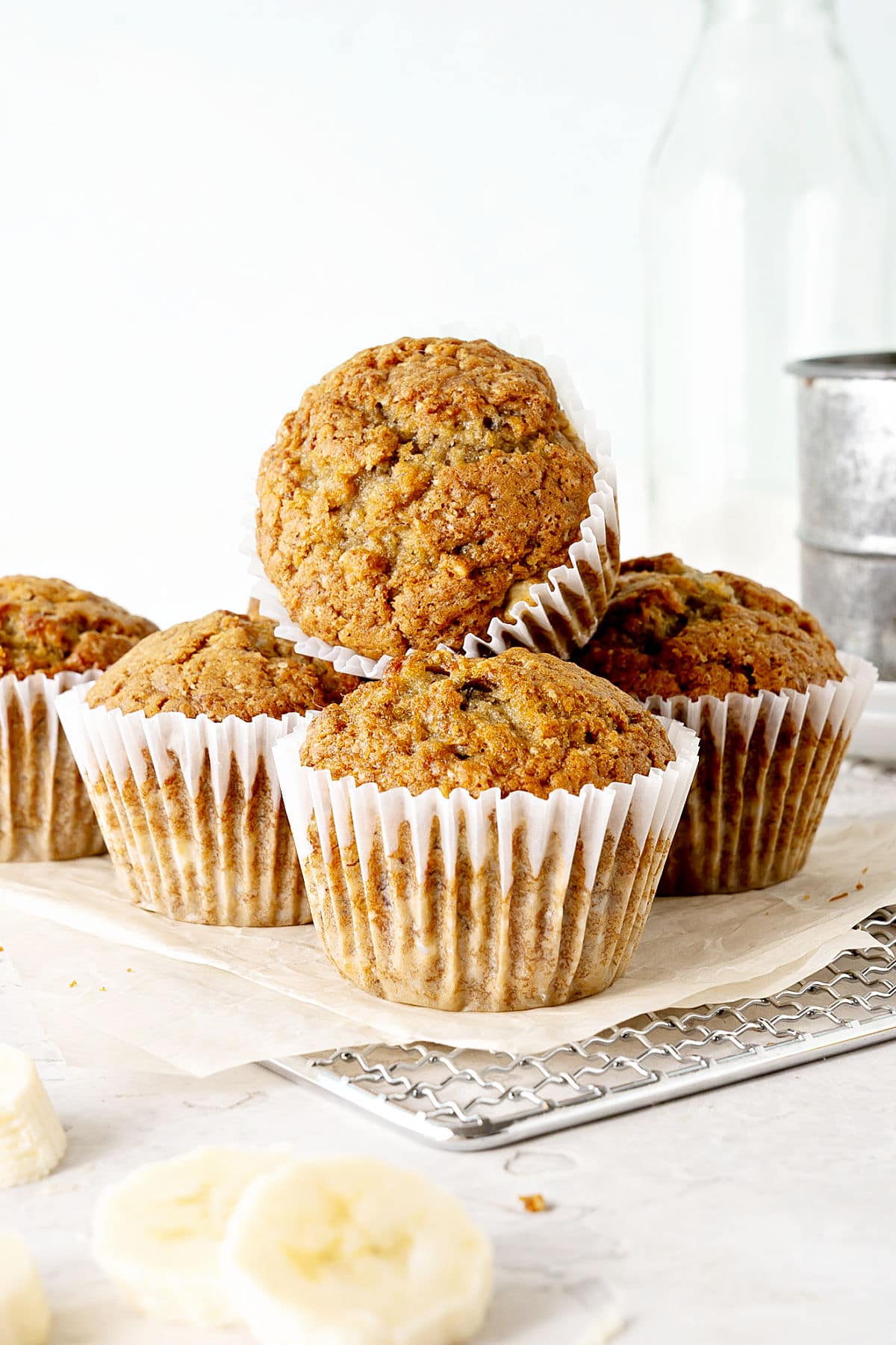 Banana muffins in paper liners on beige paper. White background, banana slices.