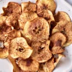 Apple chips with cinnamon sugar close up on a white plate.