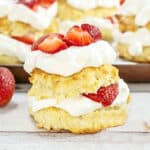 Close up fresh strawberry cream shortcake on a white wooden surface. More cakes in the background.