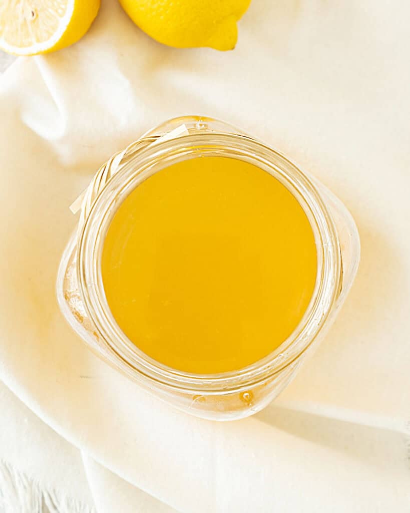 Glass jar with lemon ginger syrup on a white cloth.