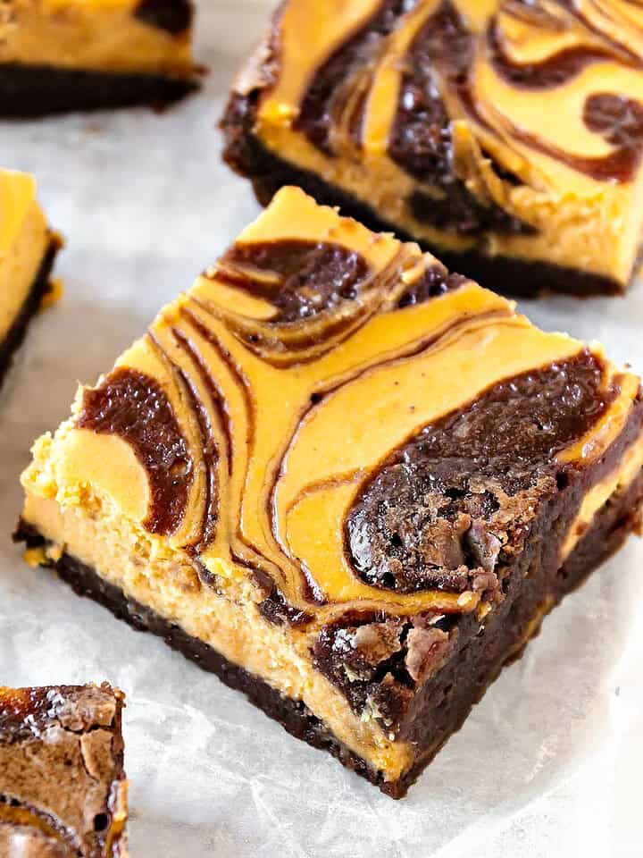 White paper with squares of pumpkin cheesecake swirl brownies.