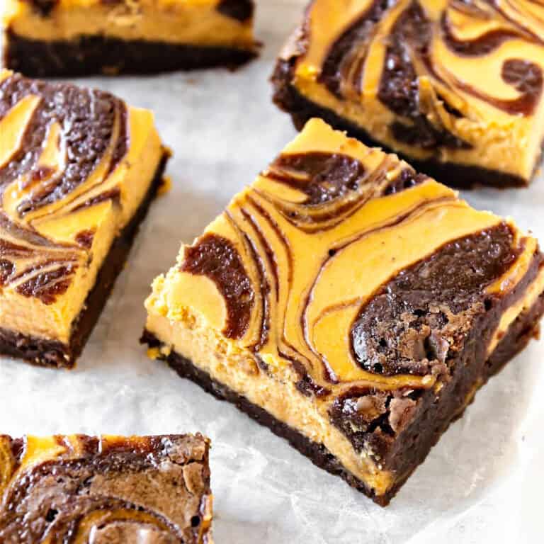 White paper with squares of pumpkin cheesecake swirl brownies.