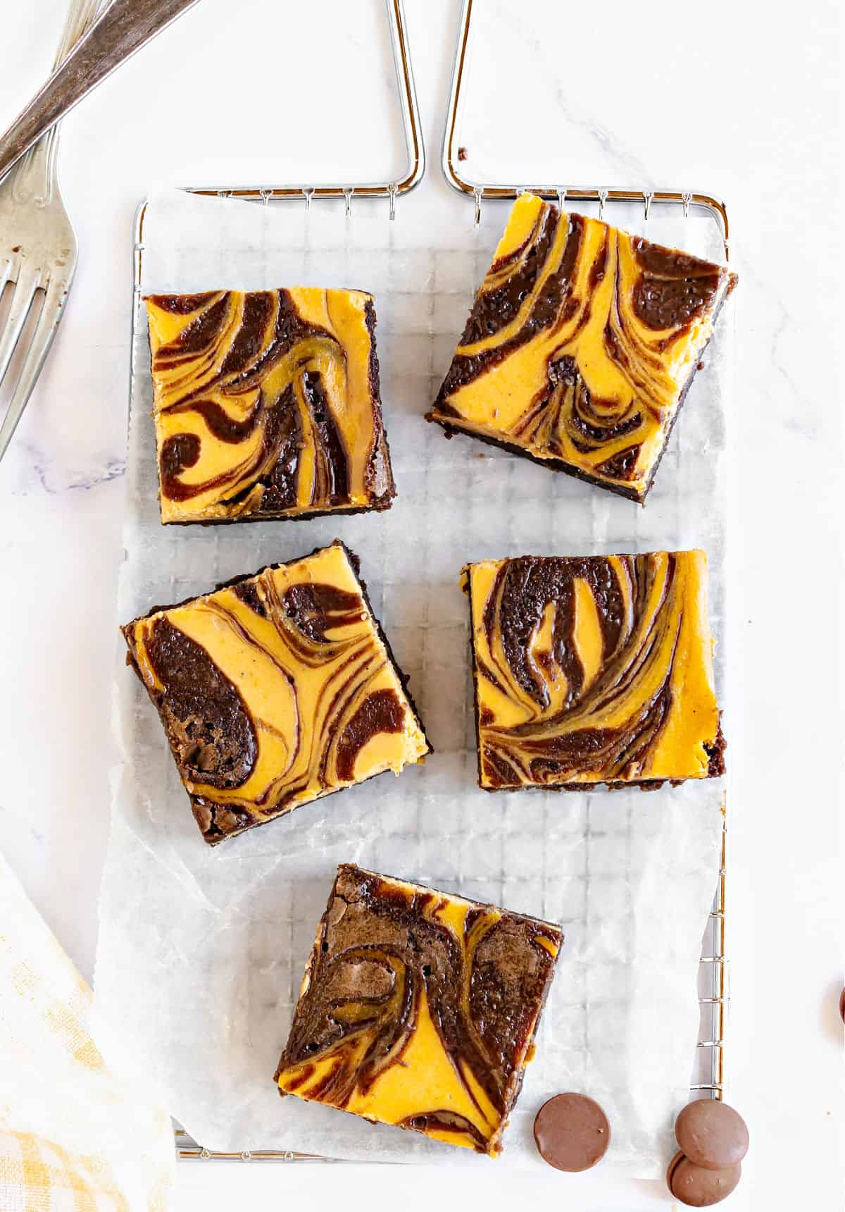 White paper on metal rack with pumpkin cheesecake brownies. White surface. Top view.