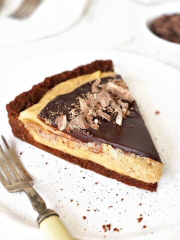 Peanut butter chocolate fudge tart on a white plate. Silver fork, white background.