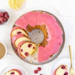 Glazed raspberry bundt cake on a white surface. Lemon slices, fresh berries.