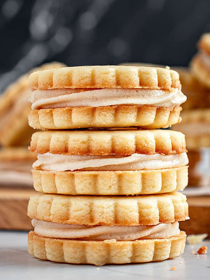 Three vanilla sandwich cookies in a pile. Dark background.