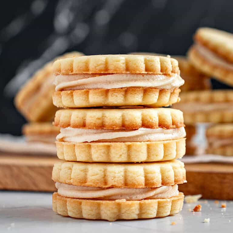 Three vanilla sandwich cookies in a pile. Dark background.