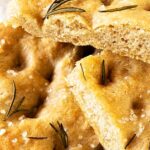 Brown, green and white text overlay on close up pieces of whole wheat focaccia.