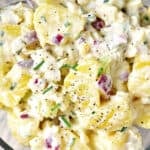 Old fashioned creamy potato salad close up, with chives, red onion and creamy dressing.