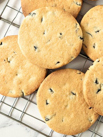 Close up top view of wire rack on a white surface with olive shortbread cookies.