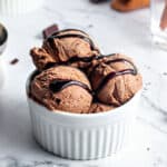 White bowl with chocolate ice cream and fudge. White marbled surface.