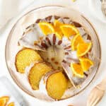 Top view of white plate with orange bundt cake with glaze. White background.