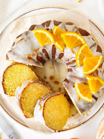 Top view of white plate with orange bundt cake with glaze. White background.