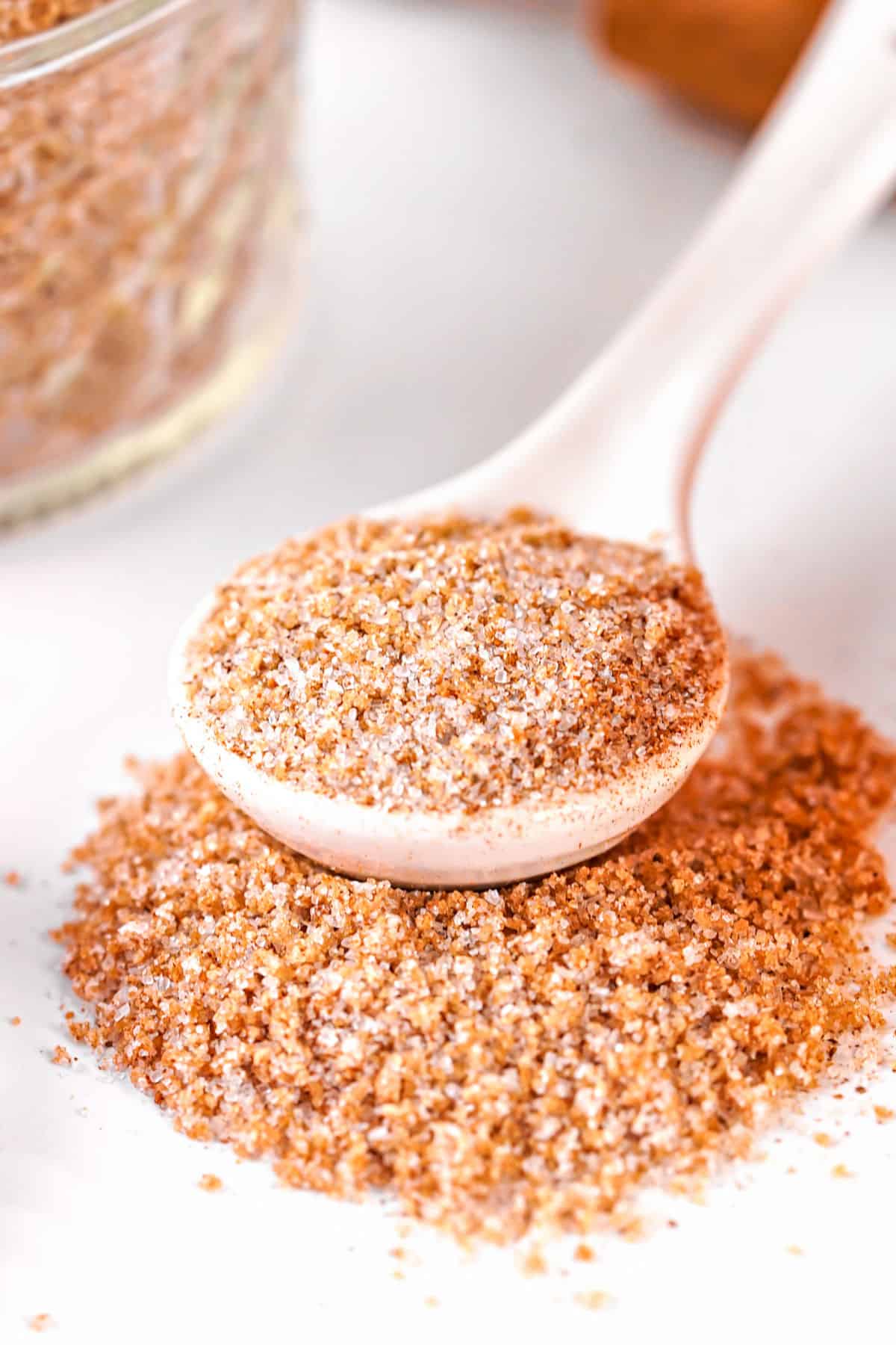 White spoon with apple cider powder mix, some spilled onto the white surface. 