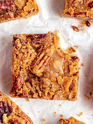 Close up of bitten maple pecan bars on white paper. Top view.