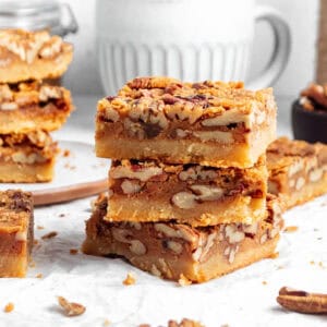 Pecan maple bars stacked on white paper. White gray bowl in the background.