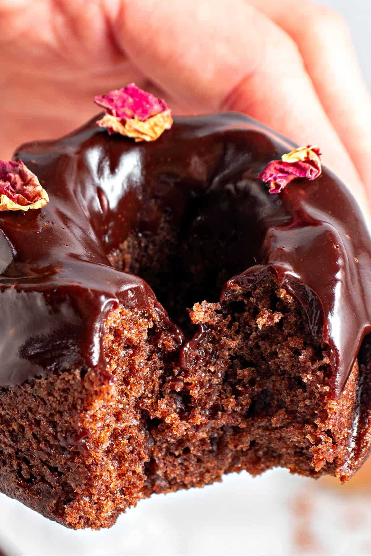 Bitten glazed mini chocolate bundt cake being held.