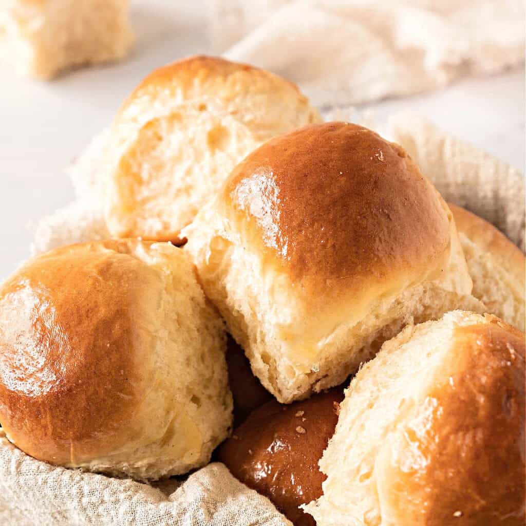 Close up yeast rolls in a basket with beige cloth. White background.