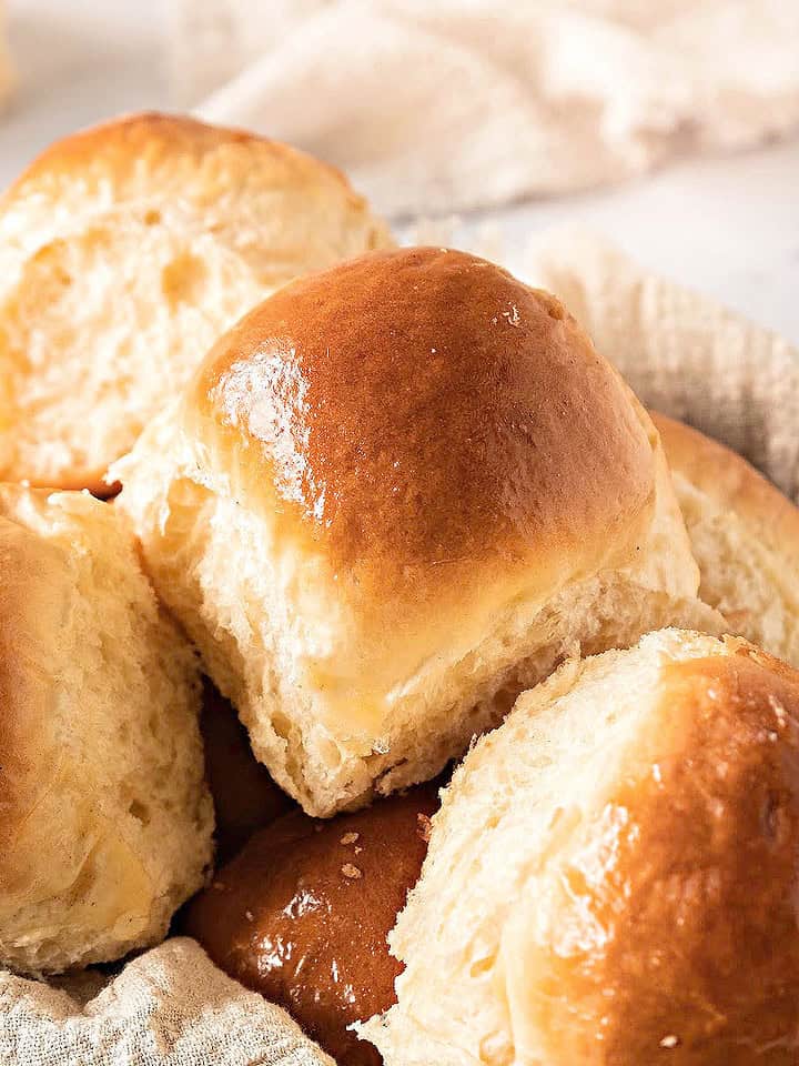 Close up yeast rolls in a basket with beige cloth. White background.